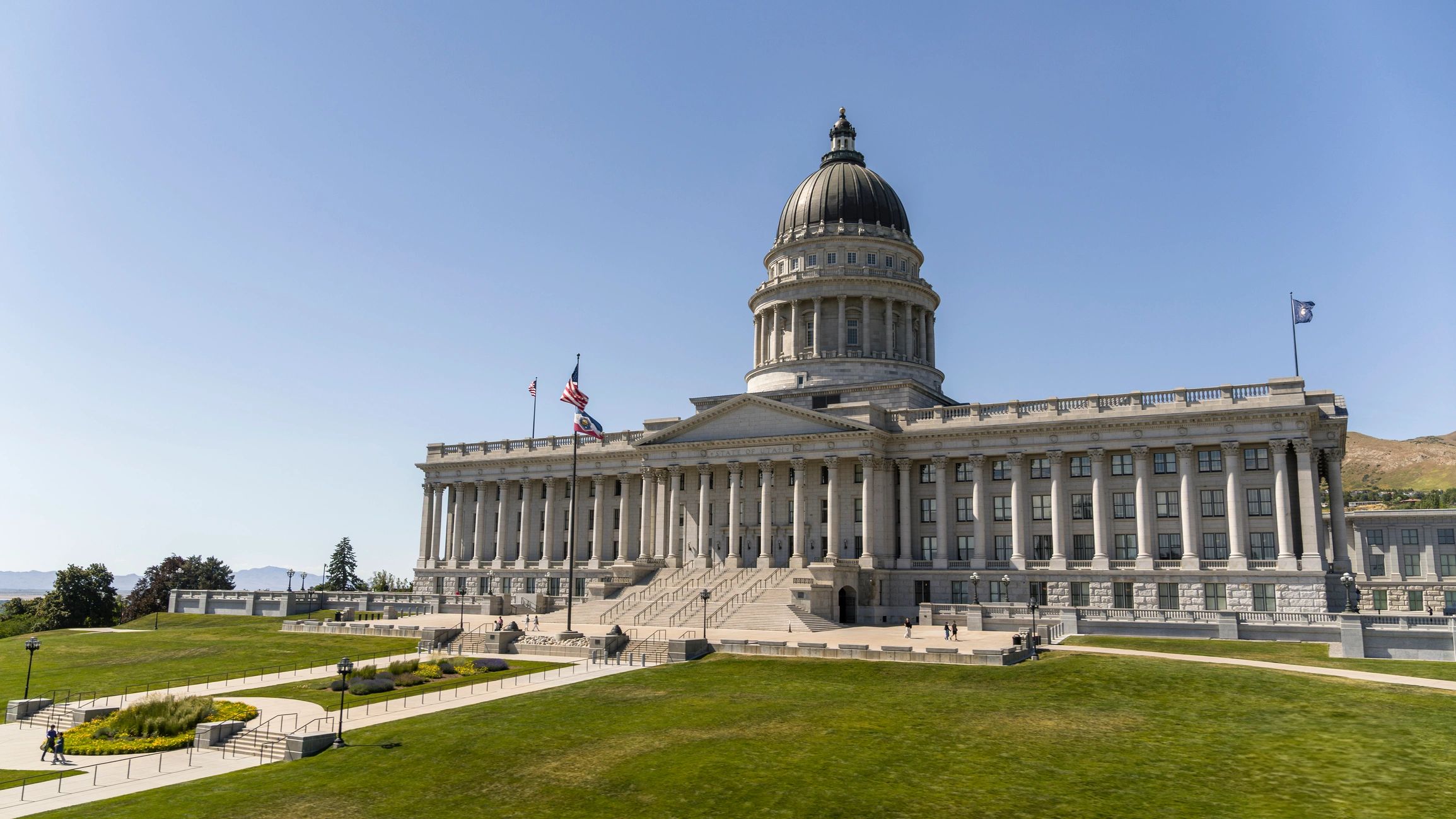 State capitol building with domed roof and flags on the grounds